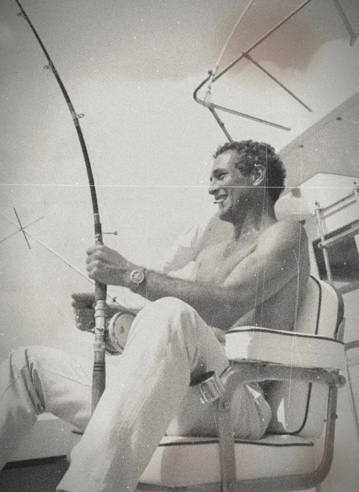 Un homme souriant pêche à la canne sur un bateau